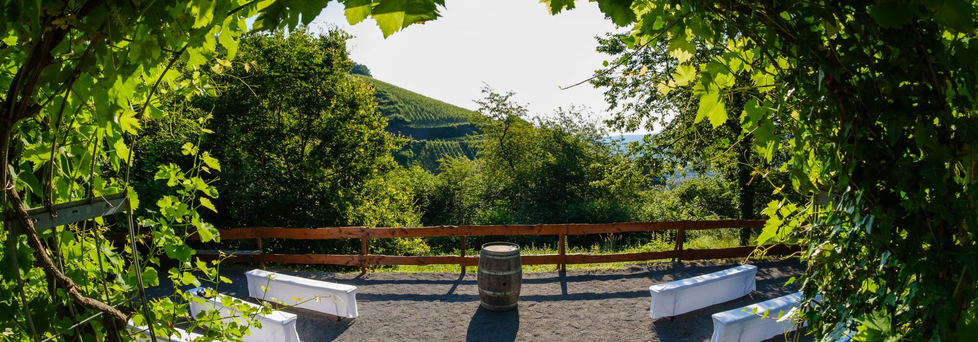 Ausblick auf Weinberge eingedeckte Tische und ein Weinfass in der Mitte