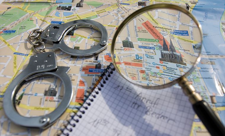 Karte einer Stadt, darau Handschellen, Notizblock und eine Lupe